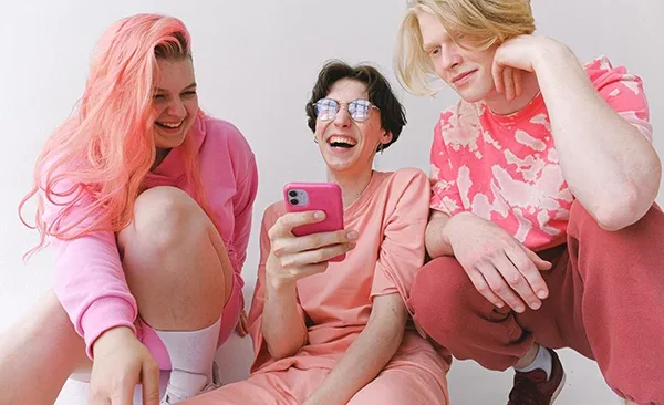 Three LGBTQ+ Gen Z women dressed in pink sitting on the floor and laughing together