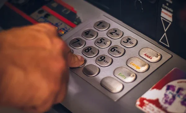 A hand entering numbers on a ATM keypad