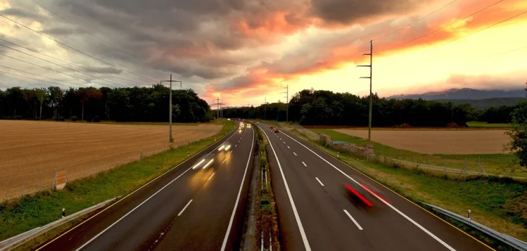 An empty road at sunset with trees and fields in the distance