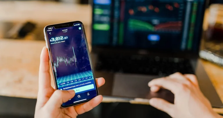 A hand holding a mobile phone with a stock ticker on the screen